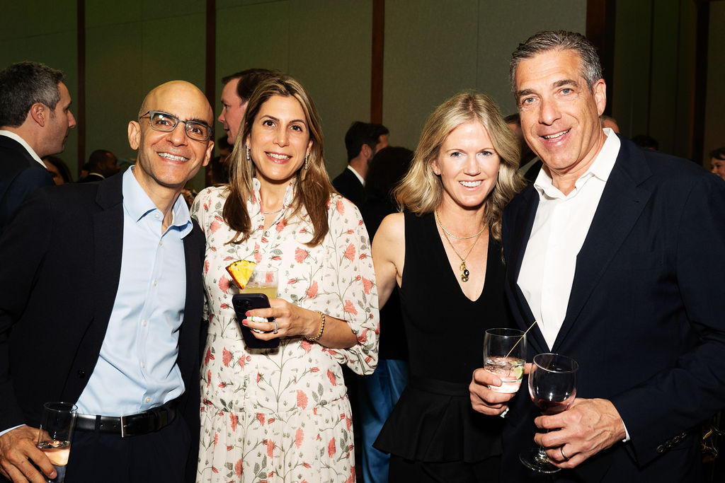 Two men and two women stand together and smile.