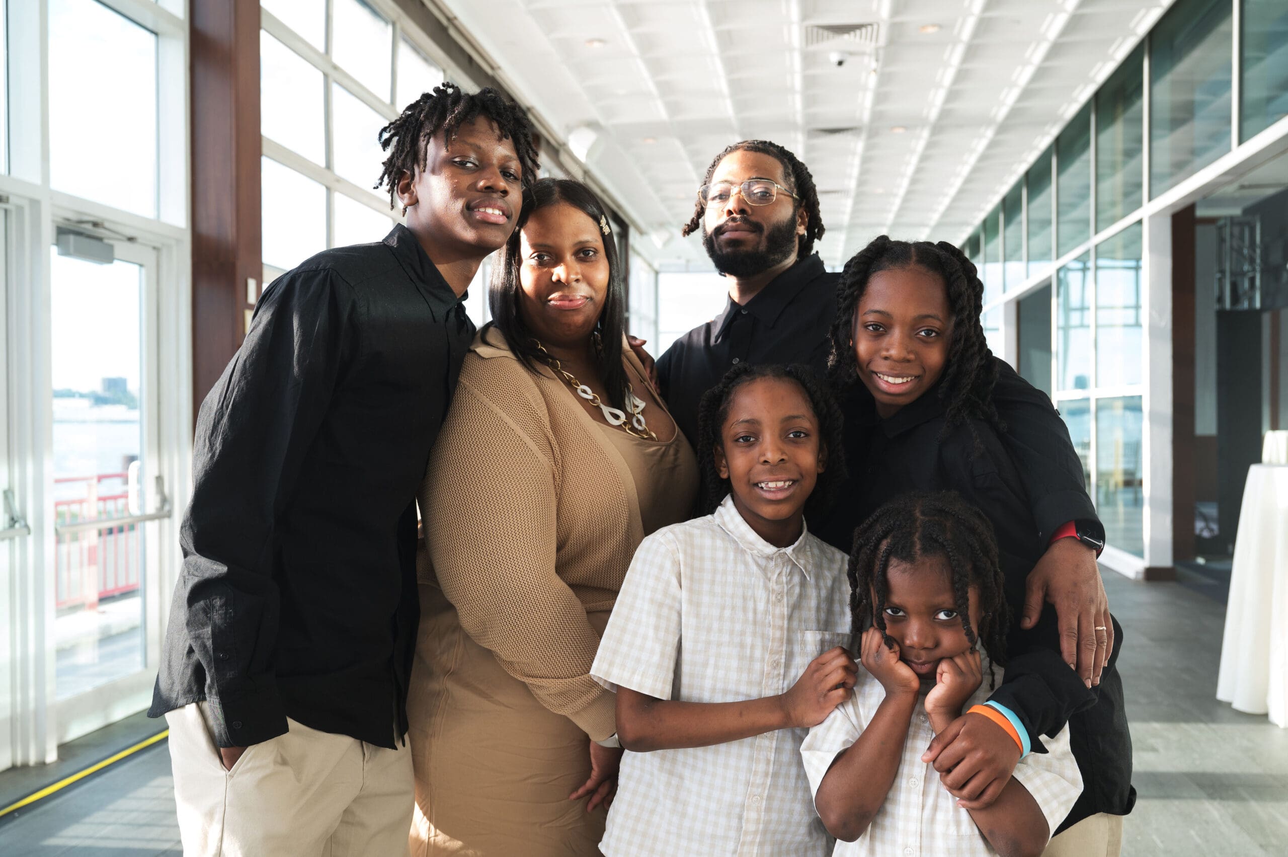 A family of six stand together and smile.