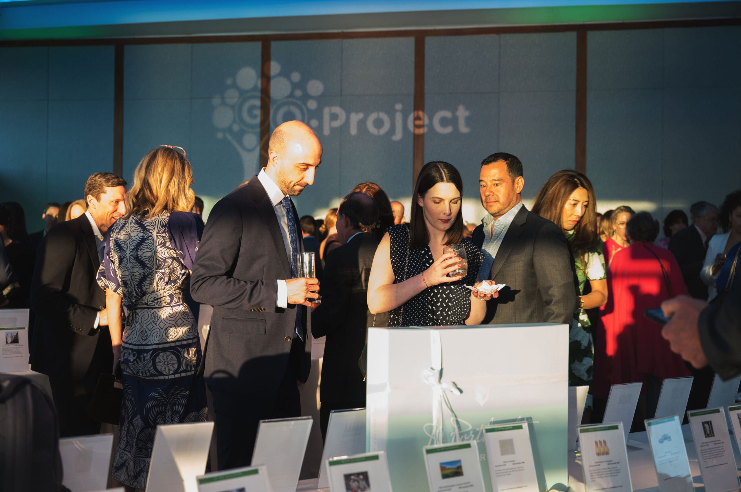 A group of gala attendees stand together and review the items held for auction.
