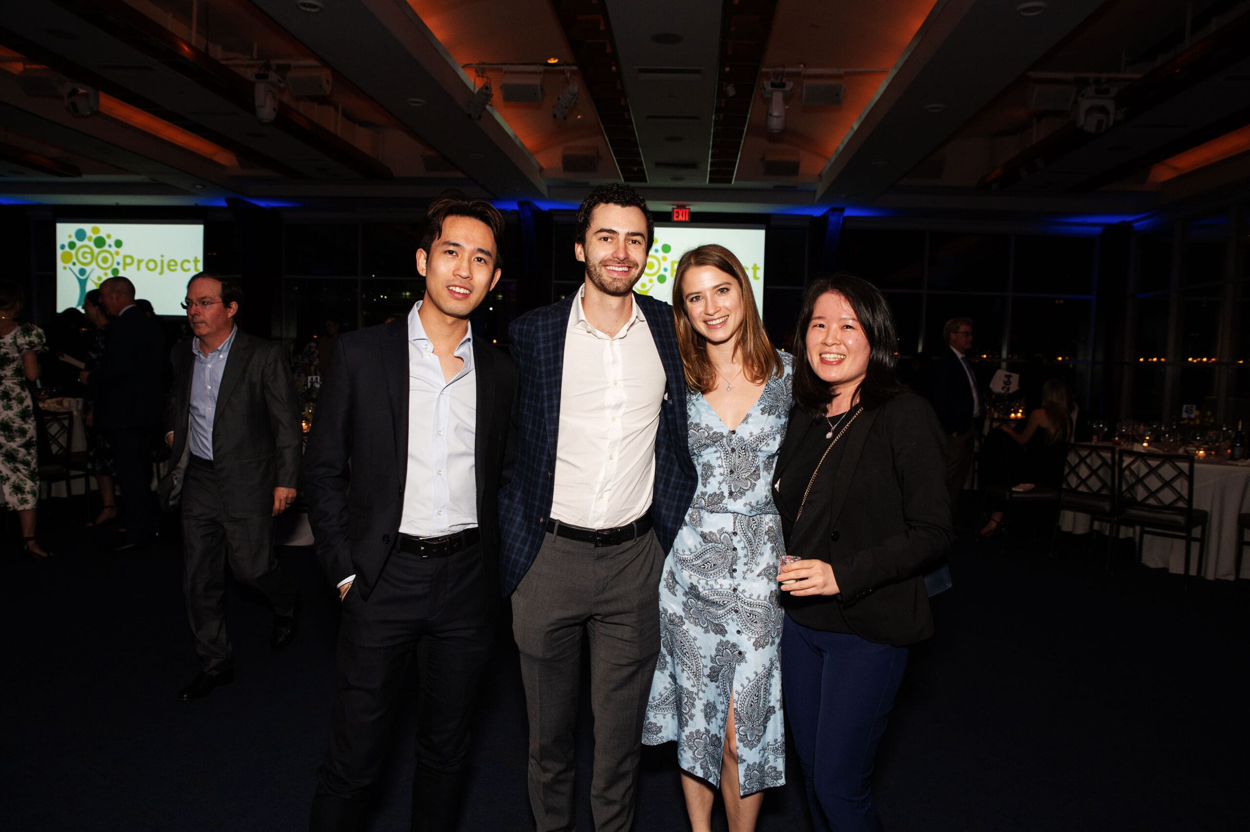 A group of people in semi-formal attire stand together and smile for a photo.