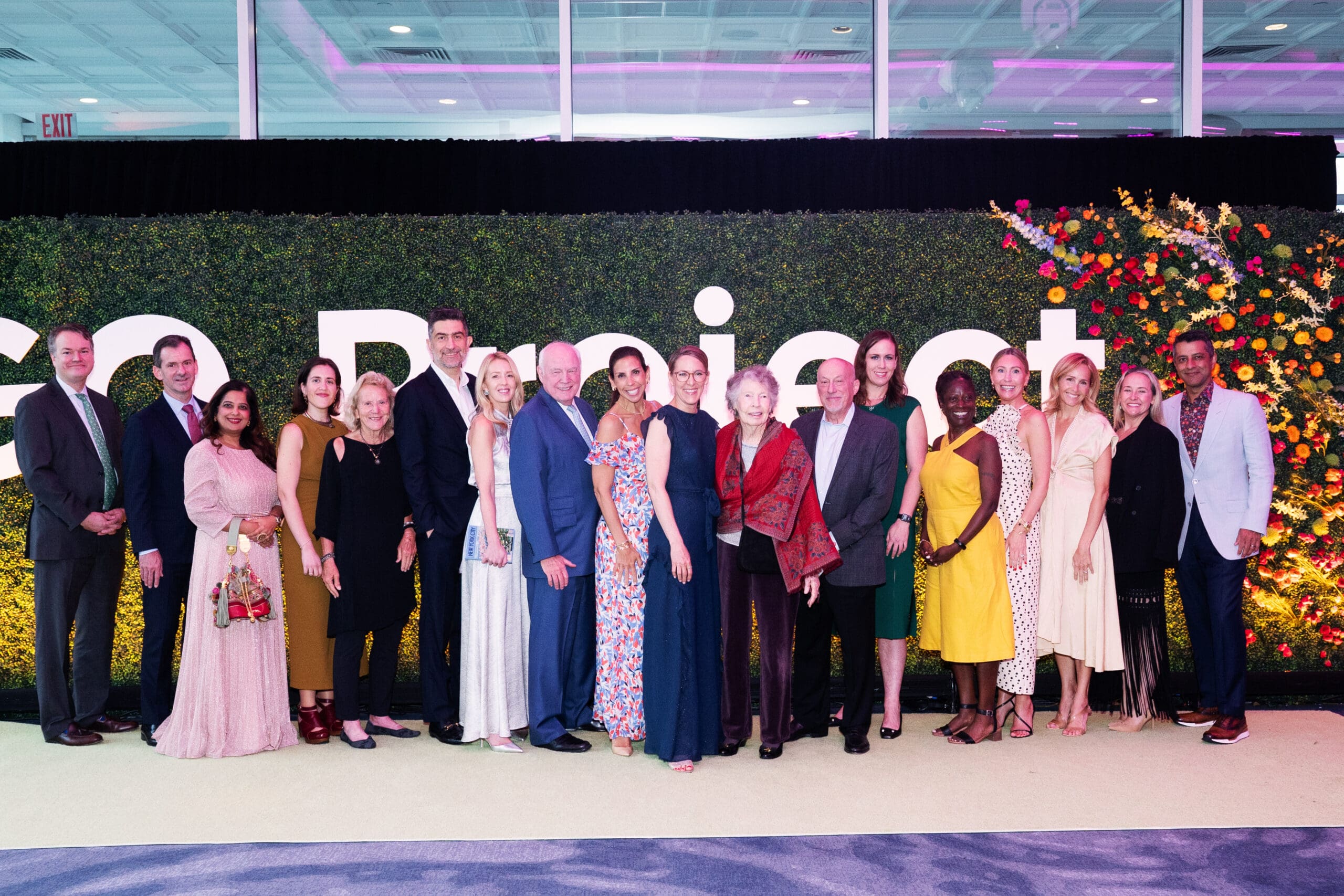 A group of attendees pose in front of a green hedge wall with white 'GO Project' lettering.