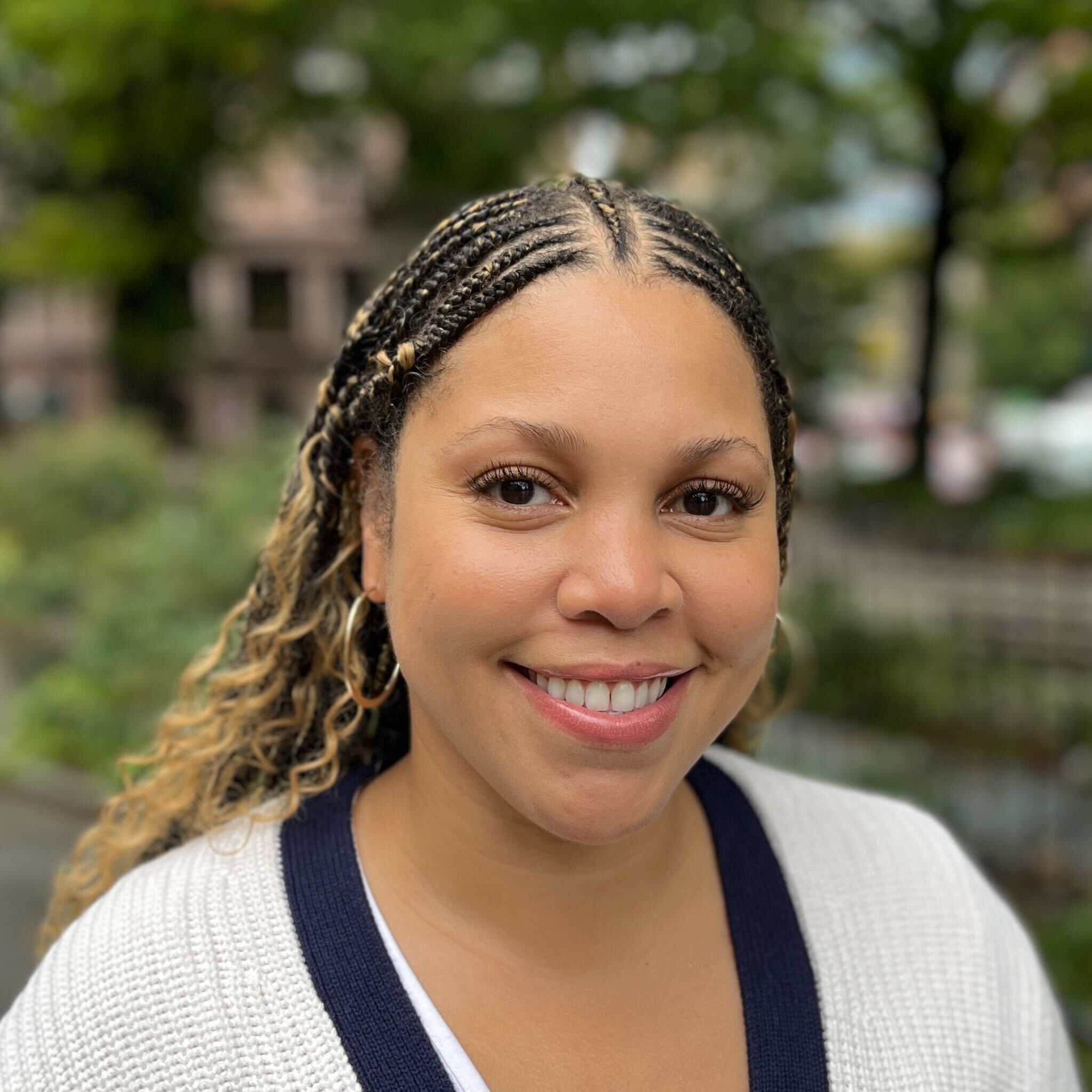 Jade Elias smiles in a lush green park.