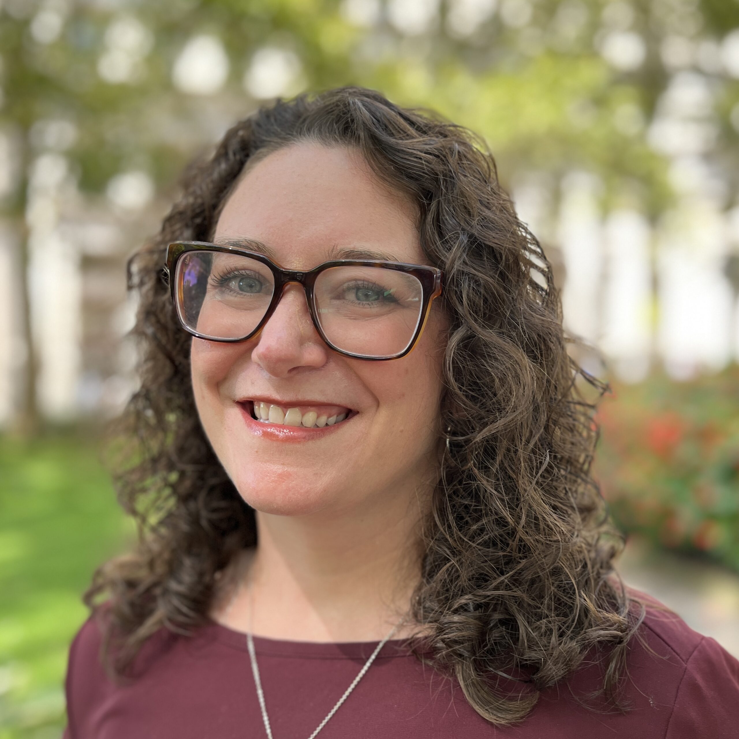 Maggie Dollard smiles in a lush green park.
