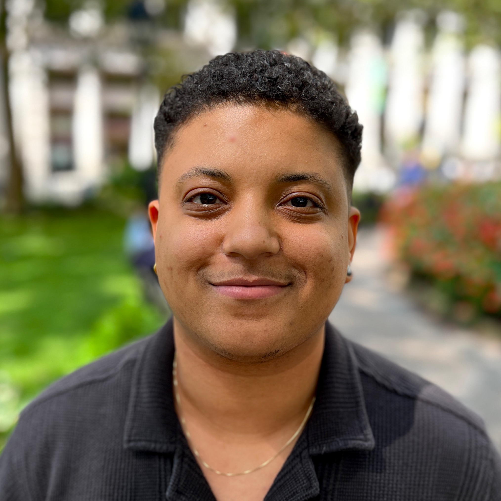 TJ Mundy smiles in a lush green park.