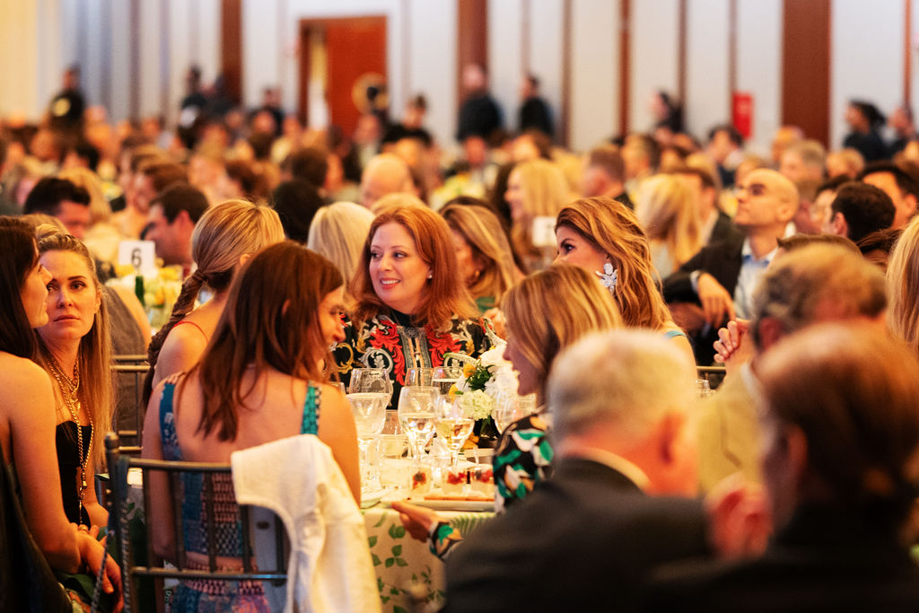 A group of attendees sit at one round table among many in an event hall for GO Project's Spring Benefit.