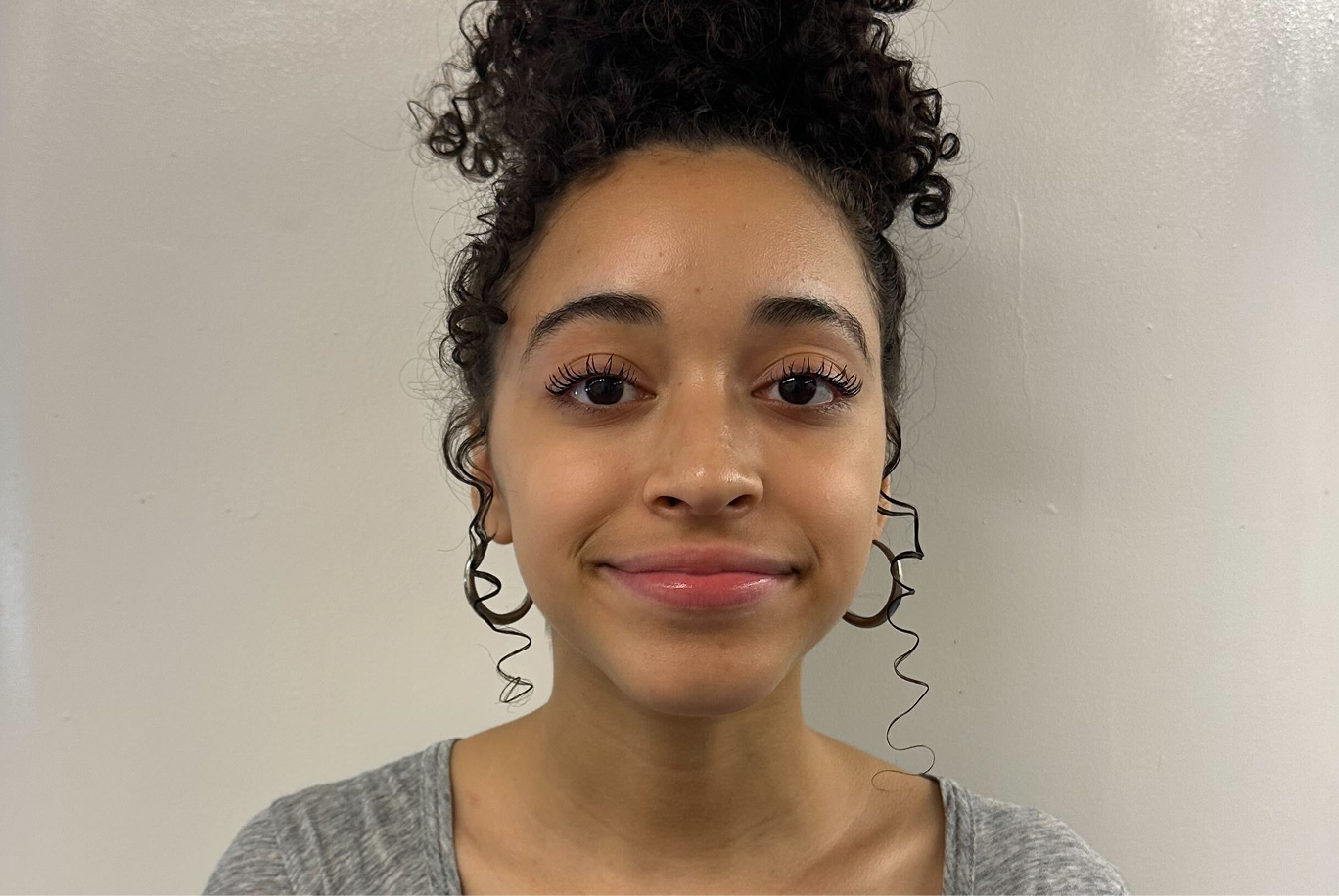 Isabella smiles in front of a wall.