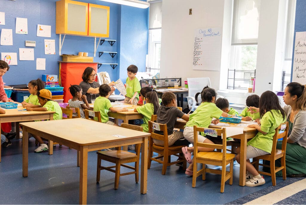 A group of students work together with instructors in a classroom.