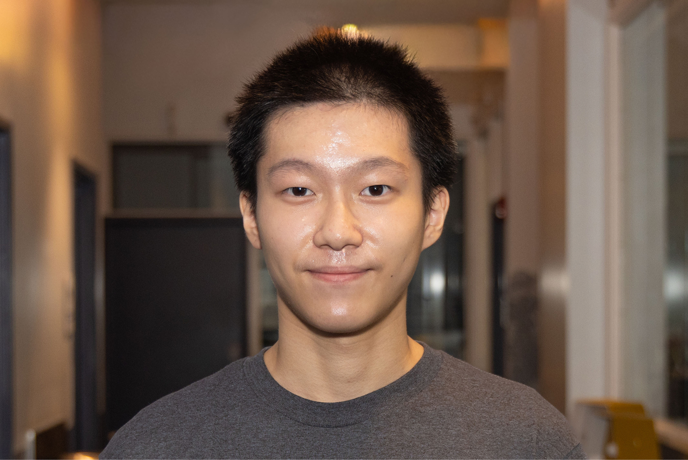 Raymond smiles in a building hallway.